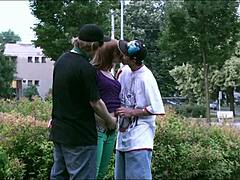 Deux mecs baisent une jeune fille blonde en public pendant que des voitures et des camions regardent dans cette vidéo de sexe de groupe