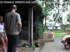Dos chicas participan en una lucha libre en un depósito de chatarra de un coche