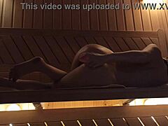 A young woman enjoys herself in the sauna with a pink dildo, experiencing orgasm