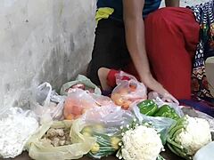 Egy szexi ruhás vörös hajú indiai lány zöldségeket árul az éhes idegeneknek